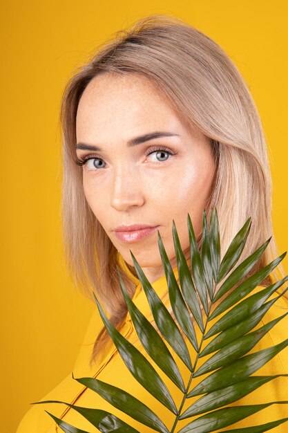 Beauty portrait of a blonde woman with good skin in yellow clothes on a yellow background