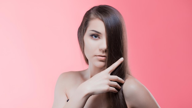 Photo beauty portrait of brunette with perfect hair on a pink background