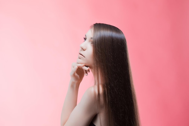 Beauty portrait of brunette with perfect hair on a pink background