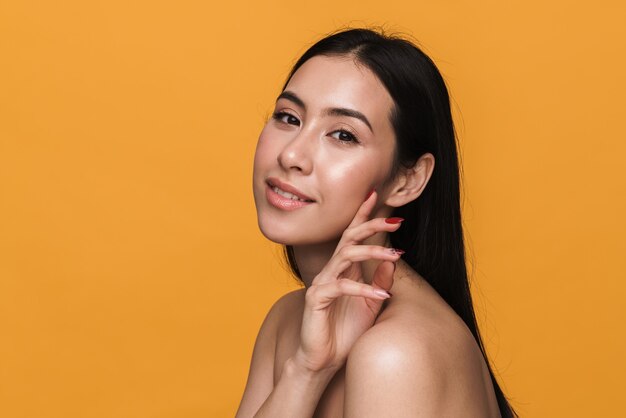 Beauty portrait of caucasian young brunette half-naked woman smiling with happy look isolated over yellow wall