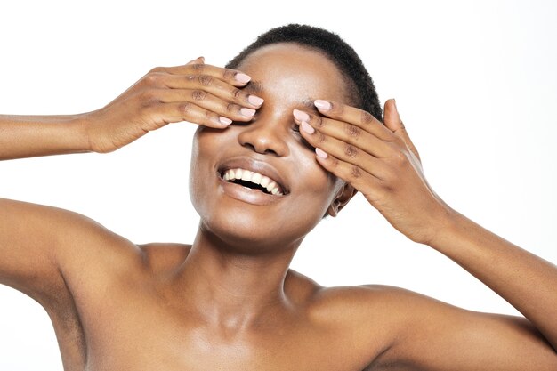 beauty portrait of a cheerful afro american woman covering her eyes isolated on a white background
