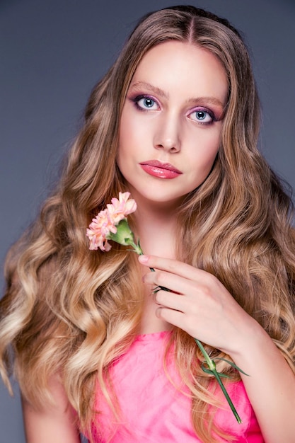 Beauty portrait of a girl Beautiful woman posing with carnation flower Facial treatments Cosmetology skin care and spa