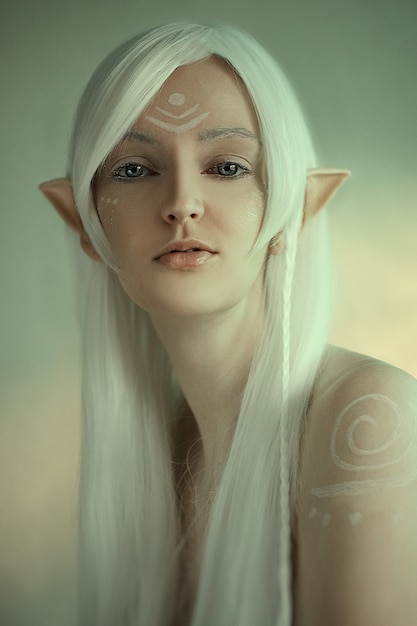 Photo beauty portrait of girl in fantasy image of an elf. white hair and faceart. long elven ears. fairy tail.