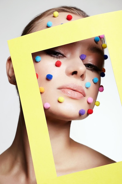 Foto ritratto di bellezza della ragazza con palline colorate sul viso