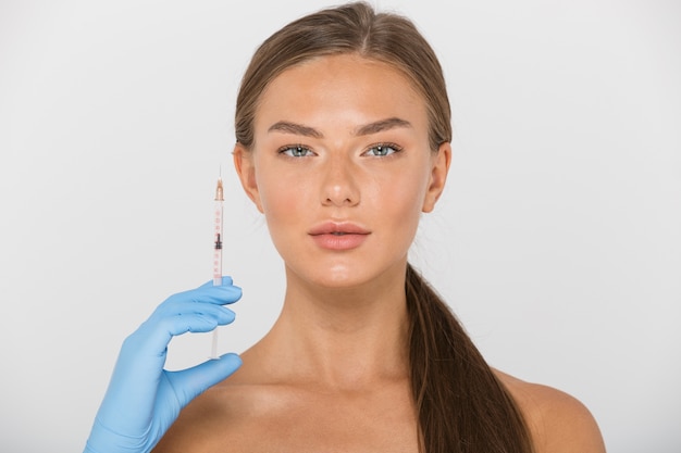 Beauty portrait of healthy shirtless woman in glove holding syringe for injection, isolated