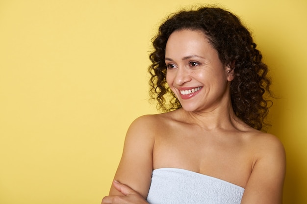 Beauty portrait of a mixed race woman with clean healthy skin on yellow wall.