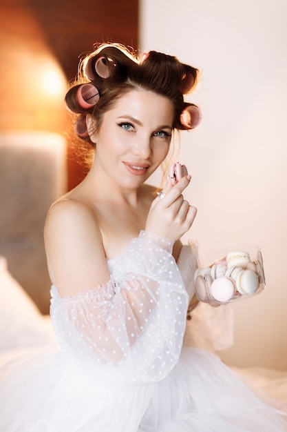 Фото Портрет красоты красивой улыбающейся молодой женщины брюнет с яркой косметикой пин ап, едящей вкусные французские миндальное печенье или macarons.