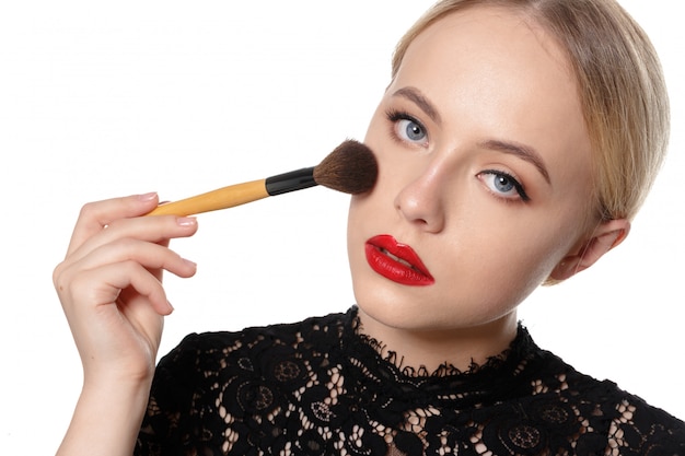 Beauty portrait of a smiling beautiful half naked woman posing with make-up brushes