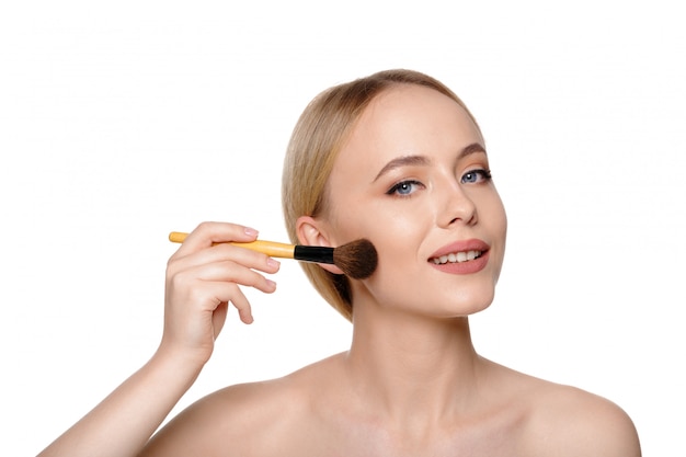 Beauty portrait of a smiling beautiful half naked woman posing with make-up brushes