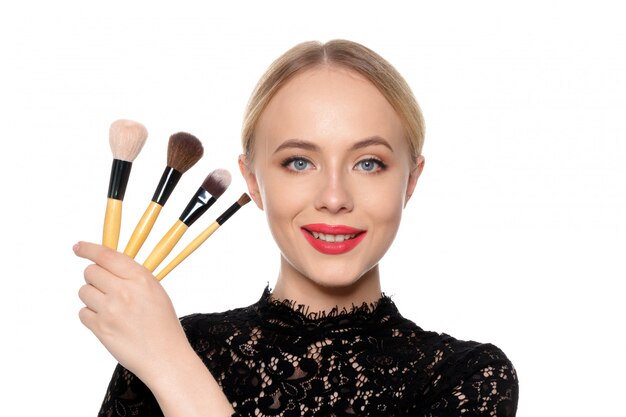 Beauty portrait of a smiling beautiful half naked woman posing with make-up brushes