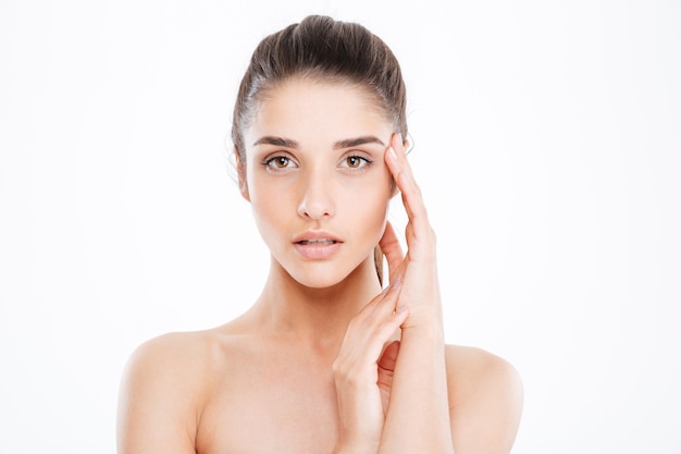 Beauty portrait of tender young woman touching her face over white wall