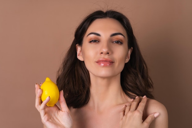Foto il ritratto di bellezza di una donna in topless con una pelle perfetta e un trucco naturale su uno sfondo beige contiene vitamine c di agrumi e limone per la pelle