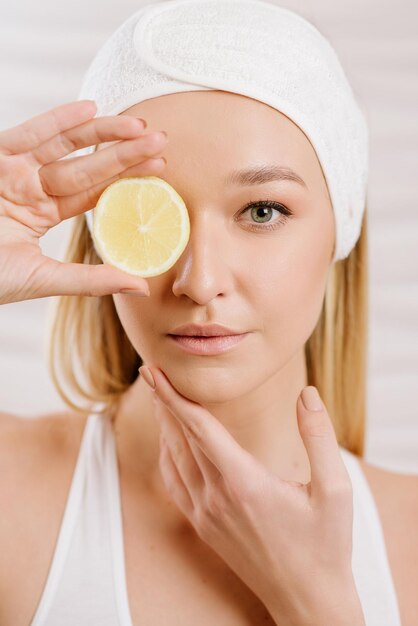 Beauty portrait of woman holding a half of lemon on white background