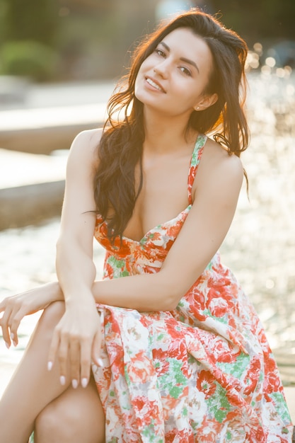 Beauty portrait of woman outdoors. Attractive stylish young female near the fountain in summertime.Closeup portrait of cheerful girl.