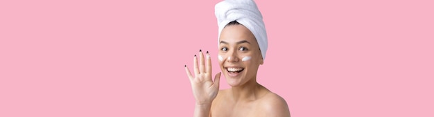 Beauty portrait of woman in white towel on head applies cream to the face Skincare cleansing eco organic cosmetic spa relax concept