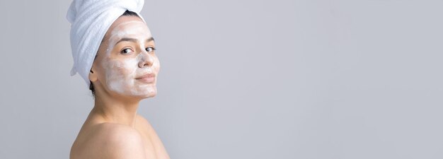 Beauty portrait of woman in white towel on head applies cream to the face Skincare cleansing eco organic cosmetic spa relax concept