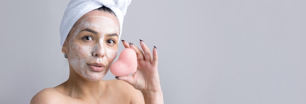 Beauty portrait of woman in white towel on head applies cream to the face Skincare cleansing