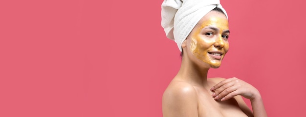 顔にゴールドの栄養マスクを頭に白いタオルで女性の美しさの肖像画スキンケアクレンジングエコオーガニック化粧品スパリラックスコンセプト