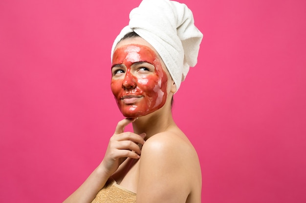 Beauty portrait of woman in white towel on head with gold nourishing mask on face