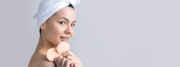 Beauty portrait of woman in white towel on head with a sponge for a body in view of a pink heart