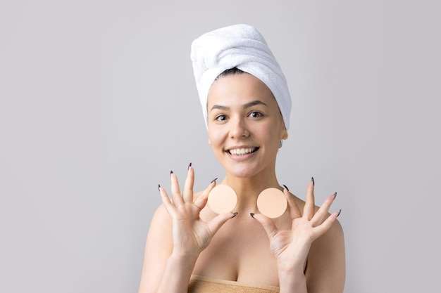 Beauty portrait of woman in white towel on head with a sponge for a body in view of a pink heart