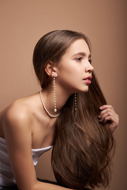 Ritratto di bellezza di una donna con gioielli, orecchini nelle orecchie e collana intorno al collo. perfetta pelle del viso pulita, cosmetici naturali