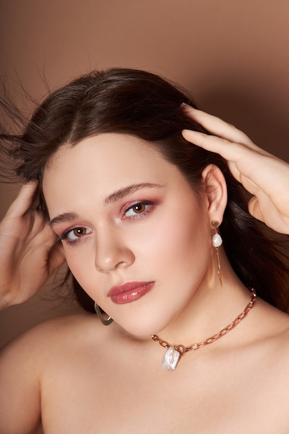 Beauty portrait of a woman with jewelry, earrings in her ears and a necklace around her neck. Perfect clean face skin, natural cosmetics