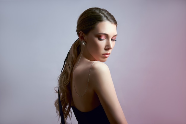 Beauty portrait of a woman with long hair, earrings in her ears and expensive jewelry on her hands