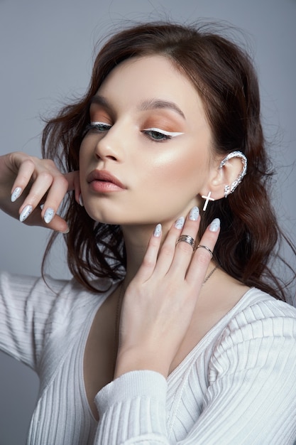 Beauty portrait of a woman with natural makeup and painted polished nails on her hand.