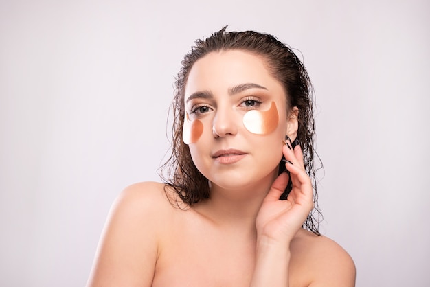 Beauty portrait of a young attractive woman with brush and perfect skin posing and looking away isolated over white.