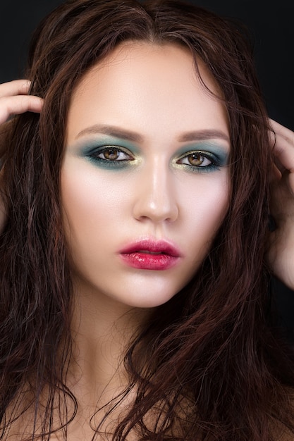Beauty portrait of young girl with fashion make-up. Green and gold smokey eyes and red lips with fuzzy outline