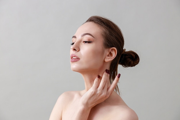  beauty portrait of a young, healthy, beautiful, fresh skinned caucasian woman on a grey wall