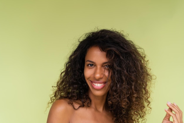 Beauty portrait of young topless african american woman with bare shoulders on green background with perfect skin and natural makeup