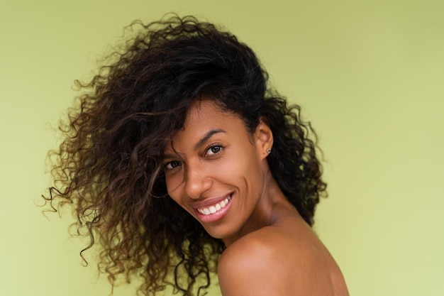 완벽한 피부와 자연스러운 화장으로 녹색 배경에 벌거벗은 어깨를 가진 젊은 토플리스 아프리카계 미국인 여성의 아름다움 초상화