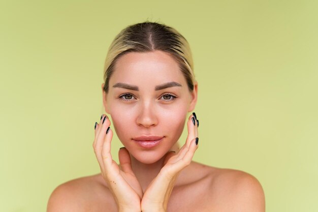 Beauty portrait of young topless woman with bare shoulders on green background with perfect skin and natural makeup