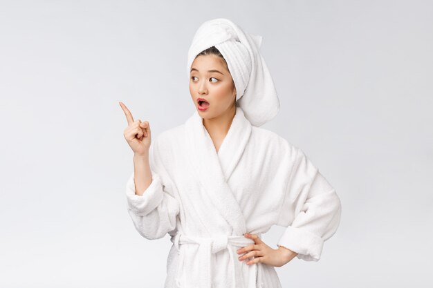 Beauty portrait of young woman showing and pointing finger to empty copy space, asian beauty in bathrobe.