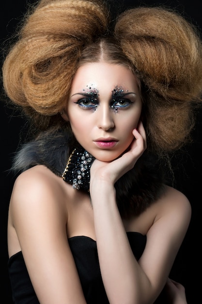 Beauty portrait of young woman with fashion makeup with rhinestones touching her face.. Carnival or party makeup