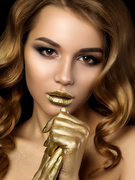 Beauty portrait of young woman with golden makeup. Perfect skin and fashion makeup with gold accents. Smokey eyes. Sensuality, passion, trendy luxurious makeup concept.