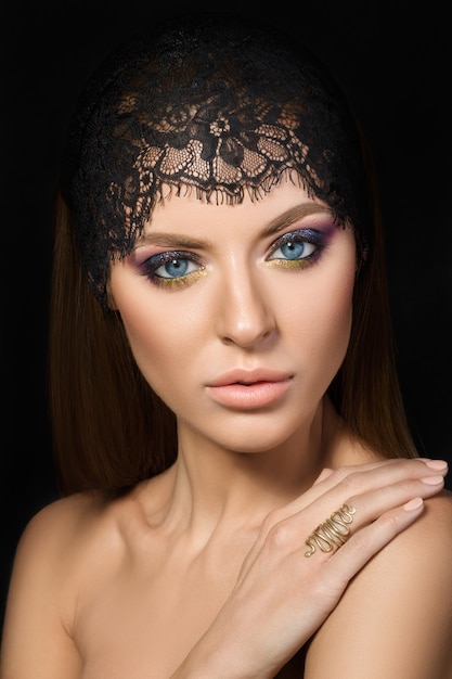 Beauty portrait of young woman with hand on her shoulder over dark background