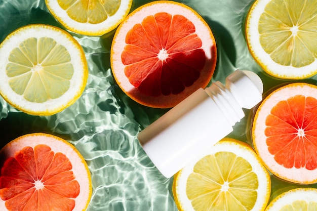 Foto rotolo di prodotti di bellezza su deodorante antitraspirante odore di sudore sulla superficie dell'acqua ondulata verde fette di pompelmo limone