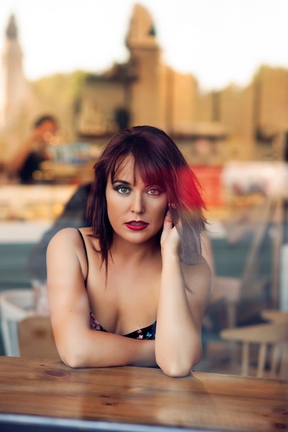 beauty redhead girl behind a glass sitting in a coffee shop 