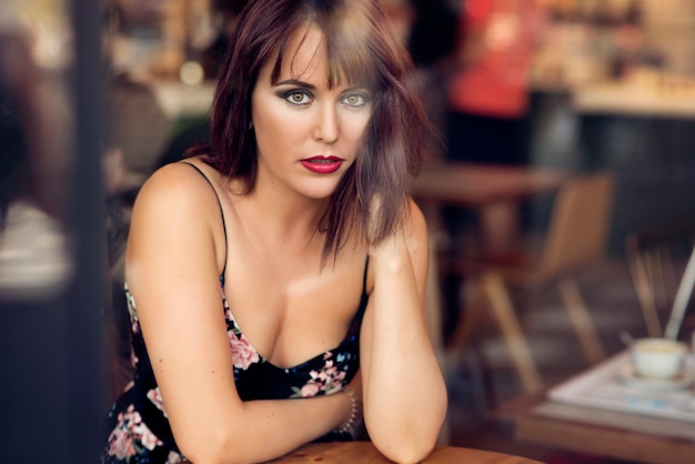 beauty redhead girl behind a glass sitting in a coffee shop 