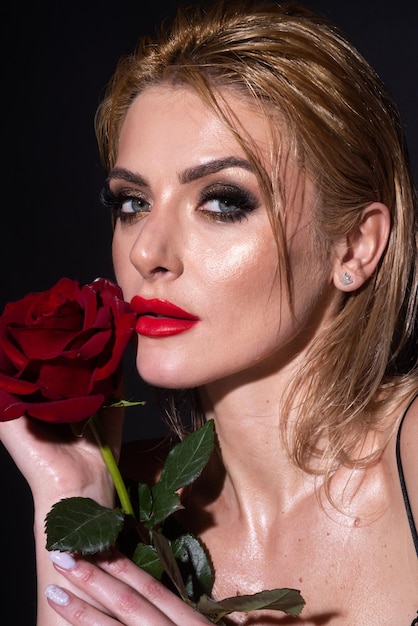 Beauty romantic woman with red rose flowers Beautiful luxury makeup Valentines Day design Portrait of fashion model girl on black studio background Unaltered face portrait