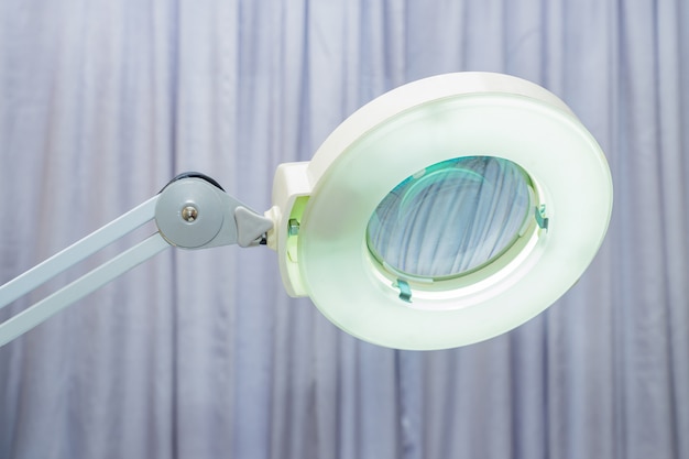 Beauty Salon equipment - lamp with a magnifying glass on gray curtains. Modern devices for performing professional cosmetological treatments