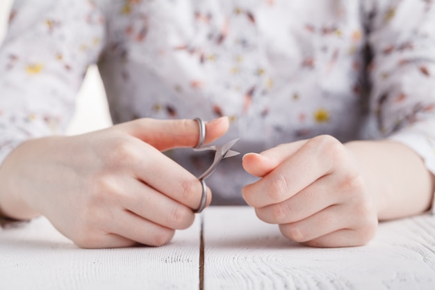 Photo beauty salon, manicure applying, cutting the cuticle with scissors