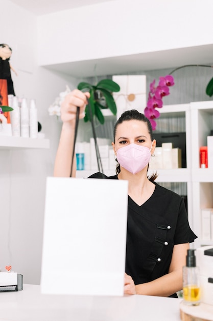 Beauty salon owner with face mask assisting customer