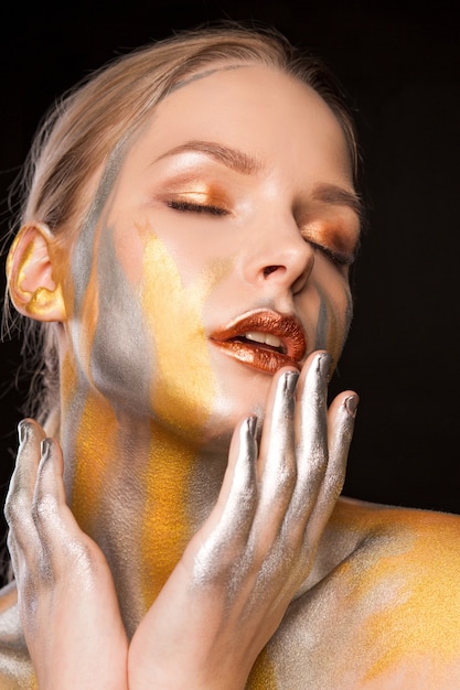 Beauty shoot of attractive blonde lady with gold and silver paint on her shoulders and face