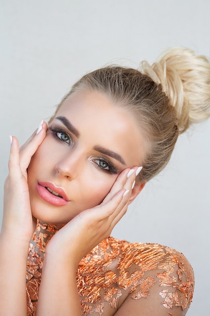 Beauty shoot of luxury blonde woman with flawless skin and golden foil on her neck and shoulders