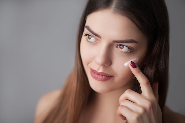 beauty skin care. beautiful happy woman applying cosmetic cream on clean face.