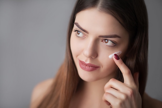 Beauty Skin Care. Beautiful Happy Woman Applying Cosmetic Cream On Clean Face.